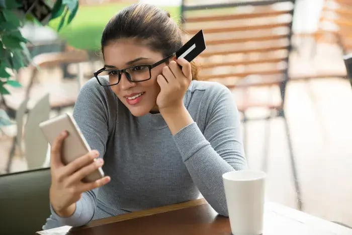 Woman purchasing eyeglasses online via smartphone after testing frames with virtual try-on.