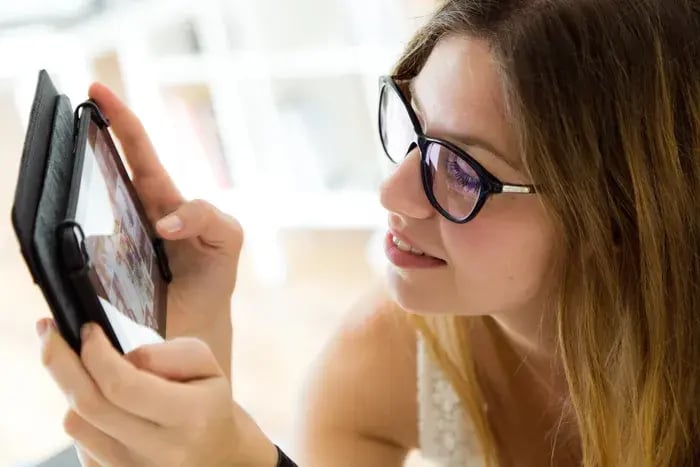 Customer browsing digital eyewear options on tablet with virtual try-on technology.