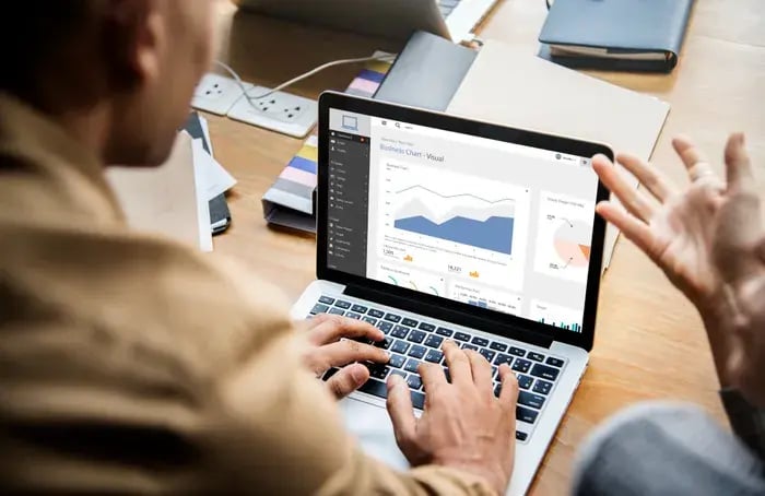 Person analyzing dashboard charts on a laptop during a discussion.
