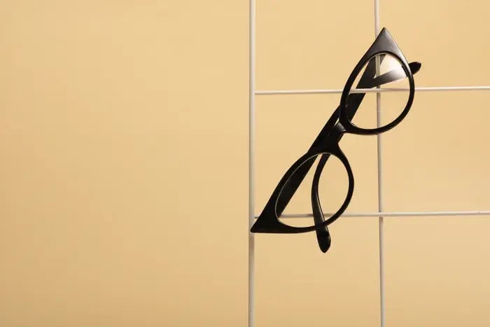 Stylish black eyeglass frames showcased against beige background for eyewear catalog.