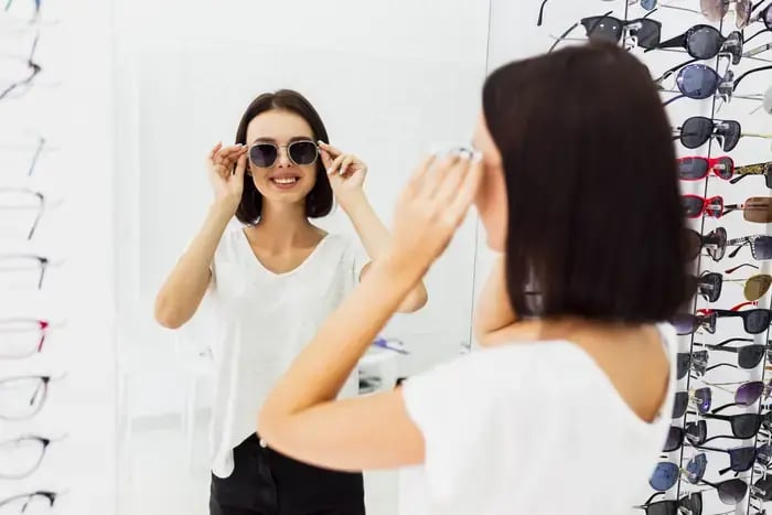 Woman trying on sunglasses in-store as part of enhanced eyewear shopping experience.