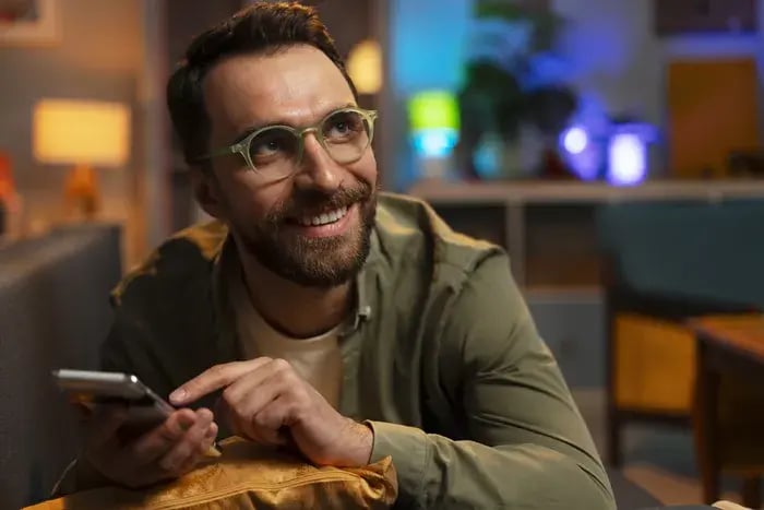 Man using mobile app for virtual try-on of eyeglasses at home.